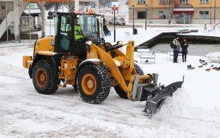 Commercial snow plow clearing large parking lot in Colorado Springs