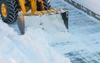 Snow plow clearing large apartment complex parking lot in Colorado Springs