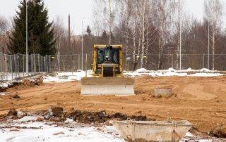 Grading equipment preparing a commercial site during winter in Colorado Springs